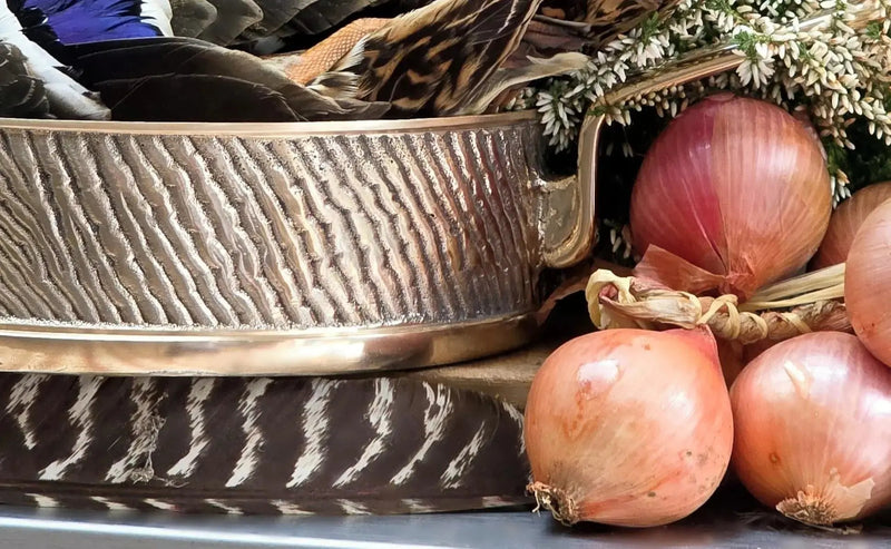 "Closeup of exquisite handcrafted Kansa bronze sauté pan Robustus surrounded by gourmet onions – naturally non-stick luxury by Eaglador".